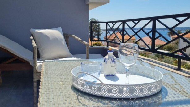 A balcony with a lounge chair, a small table with a tray, and a view of the sea. - One bedroom apartment (308) (Orebic)