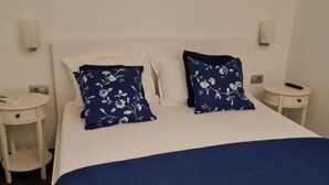 A bed with white linens and two blue floral pillows, a bedside table with a remote control, and a wall-mounted light fixture. - One bedroom apartment (308) (Orebic)