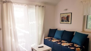 A living room with a sofa, a small table, and a remote control on the table. - One bedroom apartment (308) (Orebic)