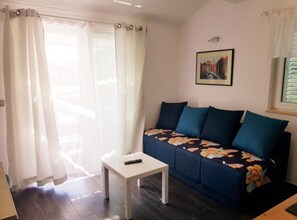 Ein Wohnzimmer mit einer Couch, einem kleinen Tisch und einer Fernbedienung auf dem Tisch.