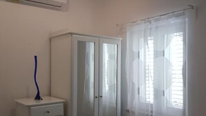 A room with a white wardrobe, a small table with a blue vase, and a window with sheer curtains. - One bedroom apartment (308) (Orebic)