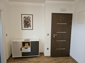 A room with a white cabinet, a framed abstract artwork, and a dark wooden door. - One bedroom apartment (702) (Orebic)