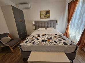 A bedroom with a bed, a bedside table, a wardrobe, a painting on the wall, and a window with curtains. - One bedroom apartment (702) (Orebic)
