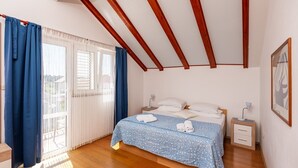 Een slaapkamer met een bed, nachtkastjes, een raam met gordijnen en een houten plafond.