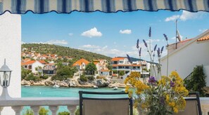 Ein Balkon mit Blick auf eine Küstenstadt, ein Pool und eine Blumenkomposition.