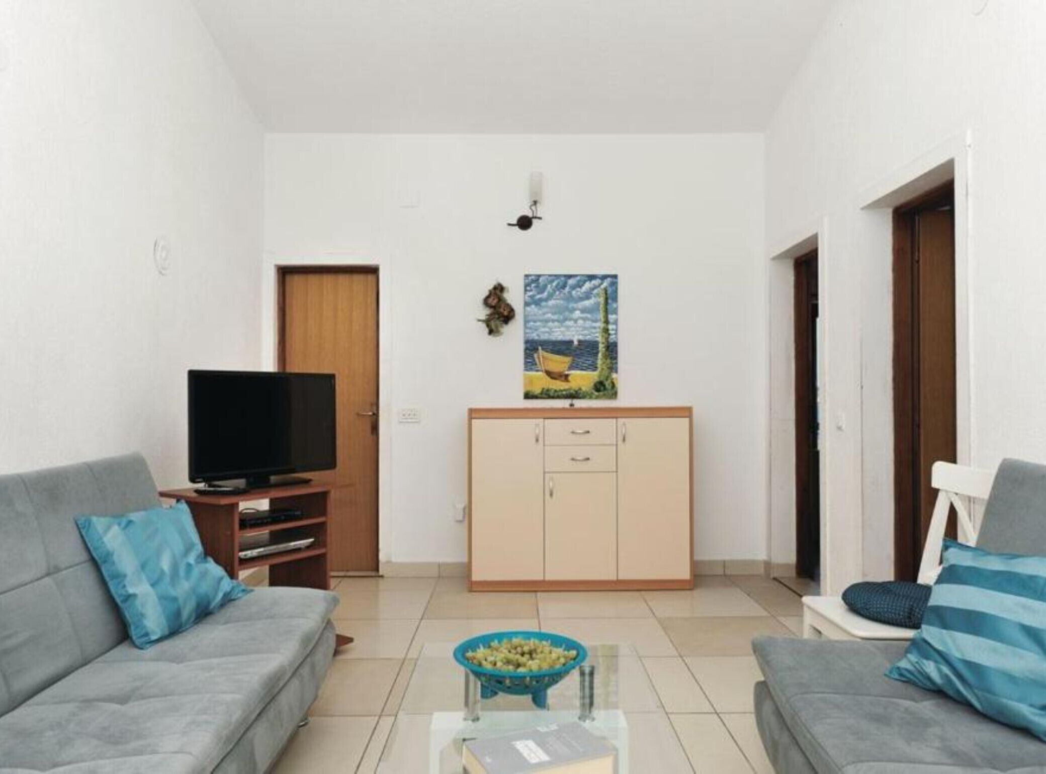 A living room with a TV, two sofas, a cabinet, and a painting on the wall.