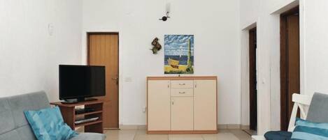 A living room with a TV, two sofas, a cabinet, and a painting on the wall.