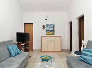 Een woonkamer met een bank, televisie, kast en een schilderij aan de muur.