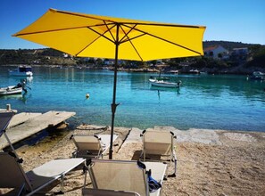 A beach with clear blue water, boats, and a yellow umbrella.