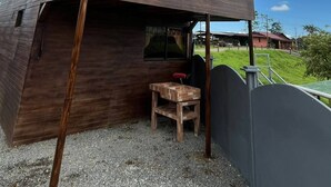 A two-story wooden house with a metal roof, a small wooden table, and a gravel ground. - Cozy 1-bedroom cabin in quaint San Carlos with AC (San Carlos)