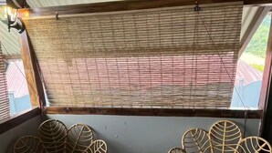 A covered outdoor seating area with wicker chairs and a small round table. - Cozy 1-bedroom cabin in quaint San Carlos with AC (San Carlos)