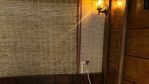 Uma banheira de hidromassagem com painel de controle, rodeada por paredes de madeira e uma janela com persianas.