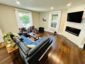 A living room with a black leather sofa, a wooden coffee table, and two armchairs.