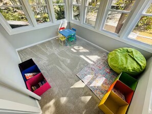 A room with large windows, a play area with colorful chairs and a table, and storage boxes. - Spacious Modern House in Dwntwn Delaware (Delaware)