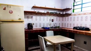 Et kompakt køkken med et køleskab, en vask, et spisebord med en stol og tapetserede vægfliser.