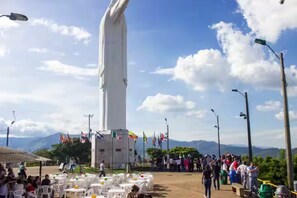 A tall white monument with a base surrounded by tables and chairs, flags, and a crowd of people. - Room with a private bathroom and kitchen (Cali)