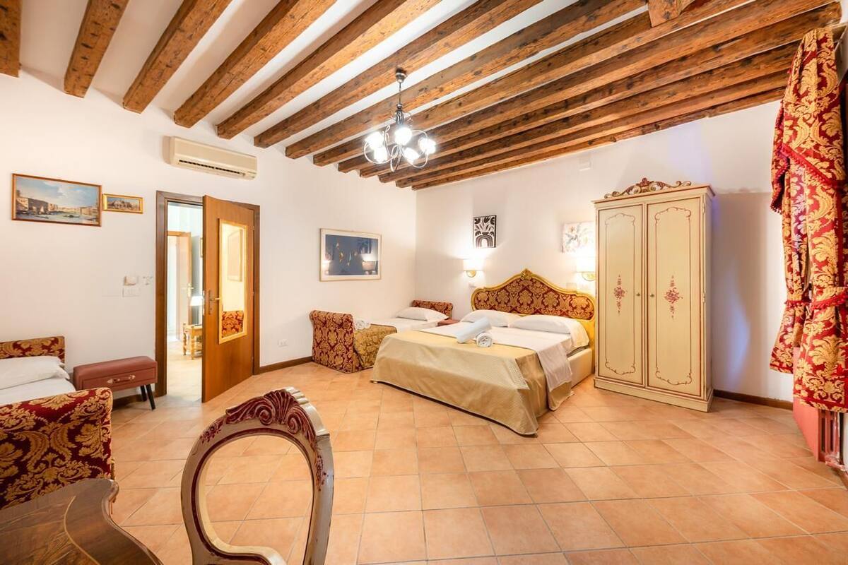 A bedroom with a bed, a wardrobe, a chair, and a door leading to another room.