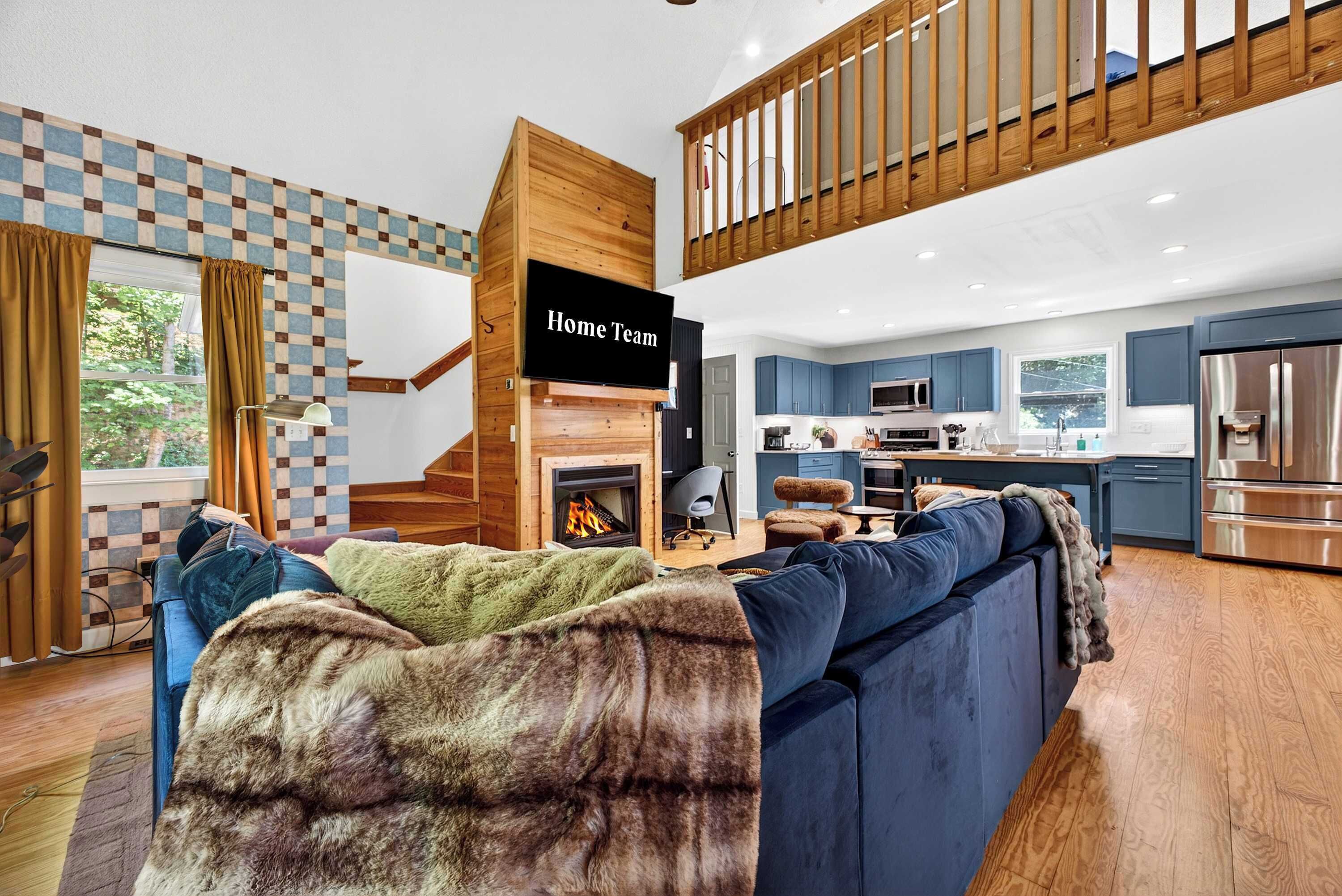 A modern living room with a fireplace, a sofa, and a kitchen area visible in the background.