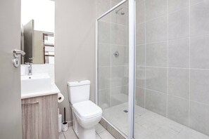 Et badeværelse med toilet, vask og brusebad.