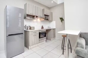 Eine moderne Küche mit Kühlschrank, Backofen und weißen Schränken.