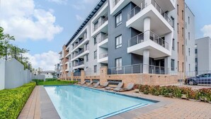A modern apartment building with a swimming pool, balconies, and a brick facade. - The Hub Serviced Apts, Bryston Backup Power Wifi (Johannesburg)