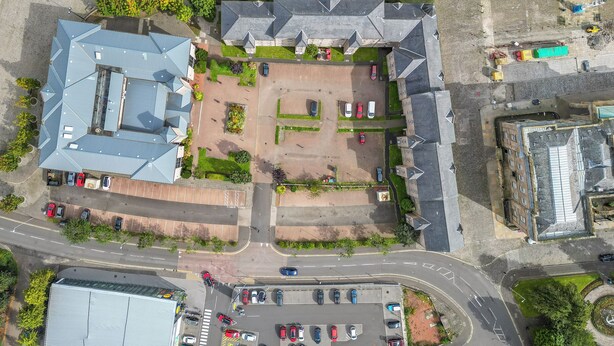 Vista aérea de un edificio con estacionamiento, una zona costera y una intersección de calles.
