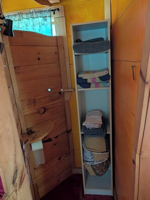 A wooden door with a latch, a shelf with folded towels, and a window with a curtain. - Tiny House Oasis in beautiful Waldo County, Maine. Dogs welcome! JUNE PRICE DROP (Jackson)