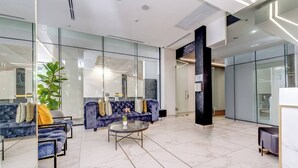 Eine moderne Lobby mit Glaswänden, zwei Sofas, einem Couchtisch und einer Topfpflanze.