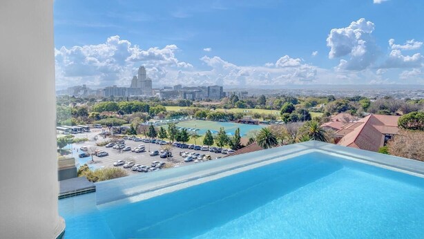 Ein Pool mit Blick auf die Stadt, einschließlich eines großen Gebäudes und eines Sportplatzes.