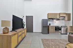 Eine moderne Küche mit Einbauofen, Kühlschrank und Mikrowelle. Ein Holzschrank beherbergt ein Fernsehen darauf.