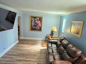 Ein Wohnzimmer mit einem braunen Ledersofa, einer Lampe und einem Gemälde an der Wand.