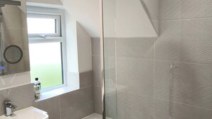 Een moderne badkamer met een douche, wastafel en raam.