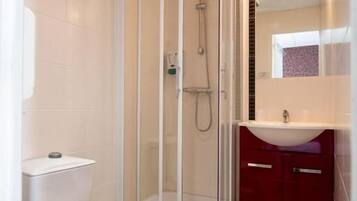 Ein Badezimmer mit Toilette, Duschkabine und Waschbecken mit Spiegel.