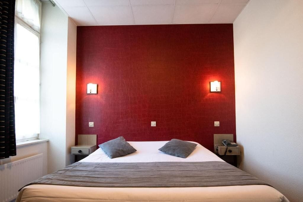 Una habitación de hotel con una cama grande, dos mesitas de noche y dos lámparas de pared.