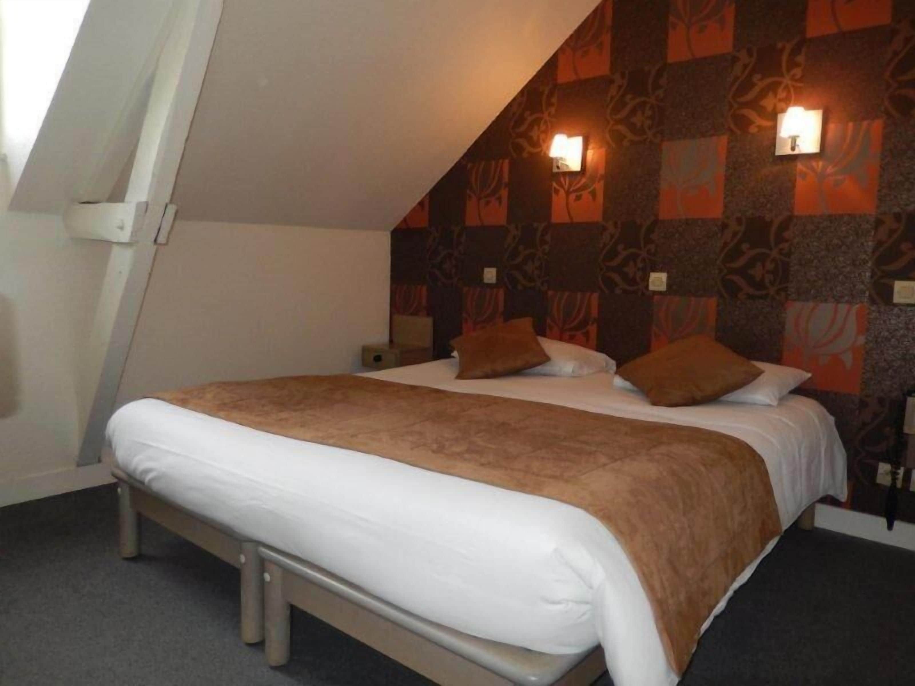 Un dormitorio con una cama, dos mesitas de noche, una ventana y un papel tapiz estampado.