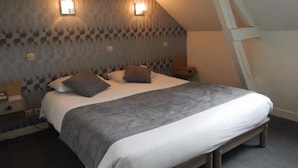 A bedroom with a bed, two bedside tables, and a sloped ceiling. - L Espérance  (Vitré)