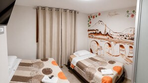 A hotel room with two beds, a curtain, a wall mural, and a ceiling light.