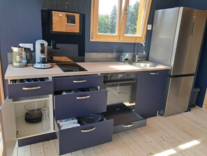 Una cocina moderna con horno integrado, refrigerador de acero inoxidable y ventana sobre el fregadero.