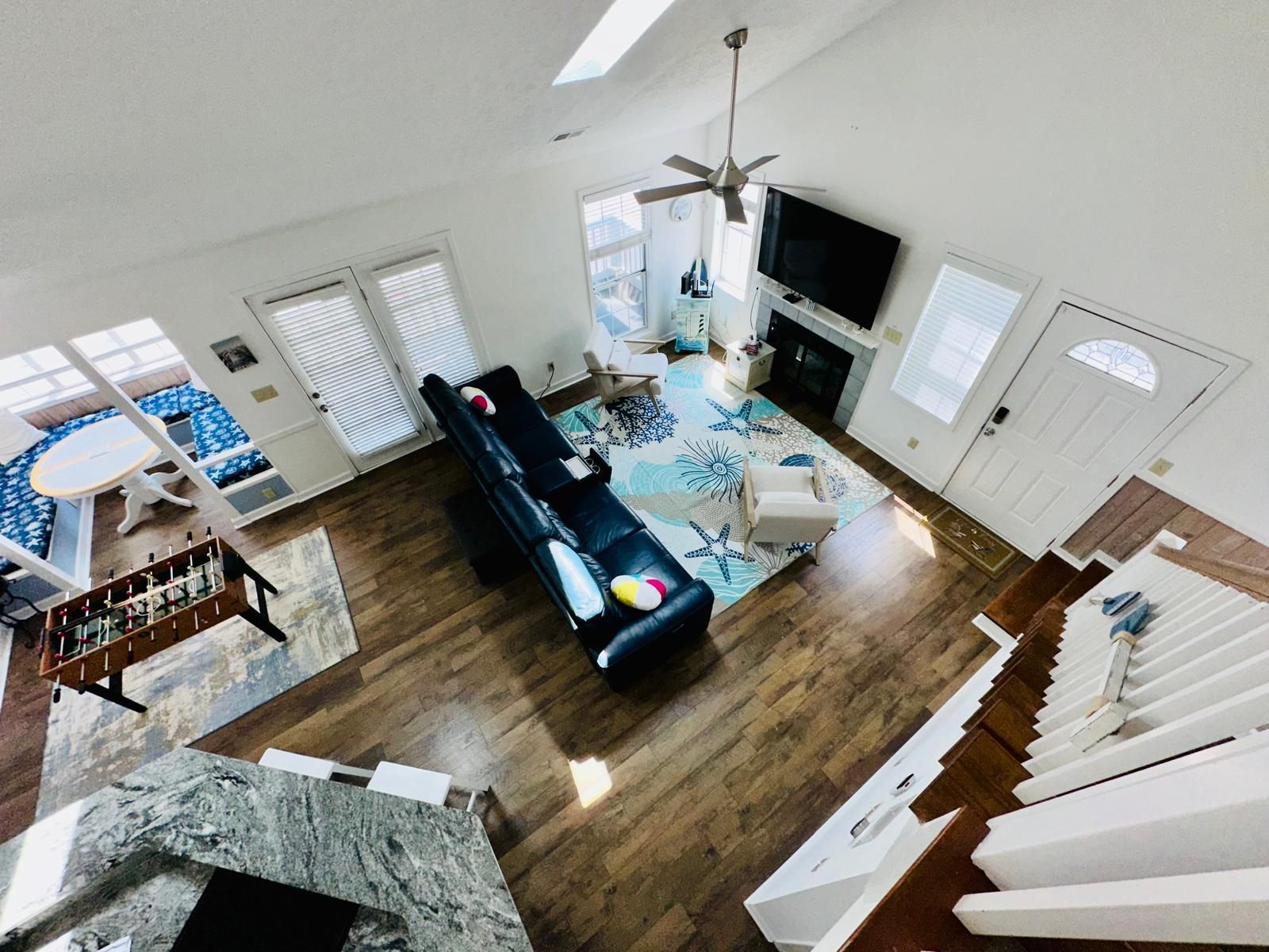 Un salon spacieux avec un grand canapé, un téléviseur et un ventilateur de plafond.