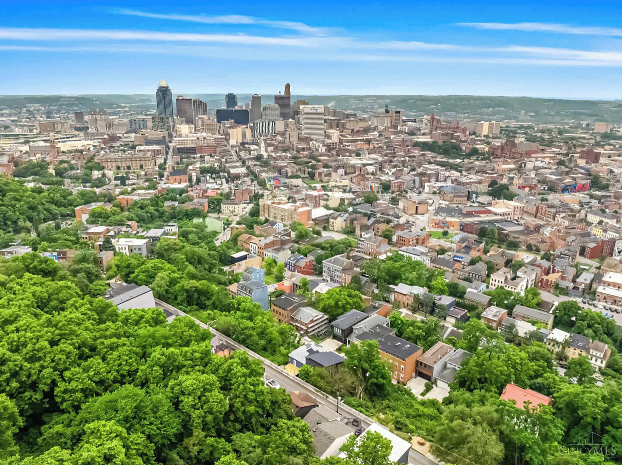 Vista aérea de uma cidade com edifícios urbanos densos, uma mistura de arranha-céus e edifícios baixos, e uma grande área de parque verde em primeiro plano.