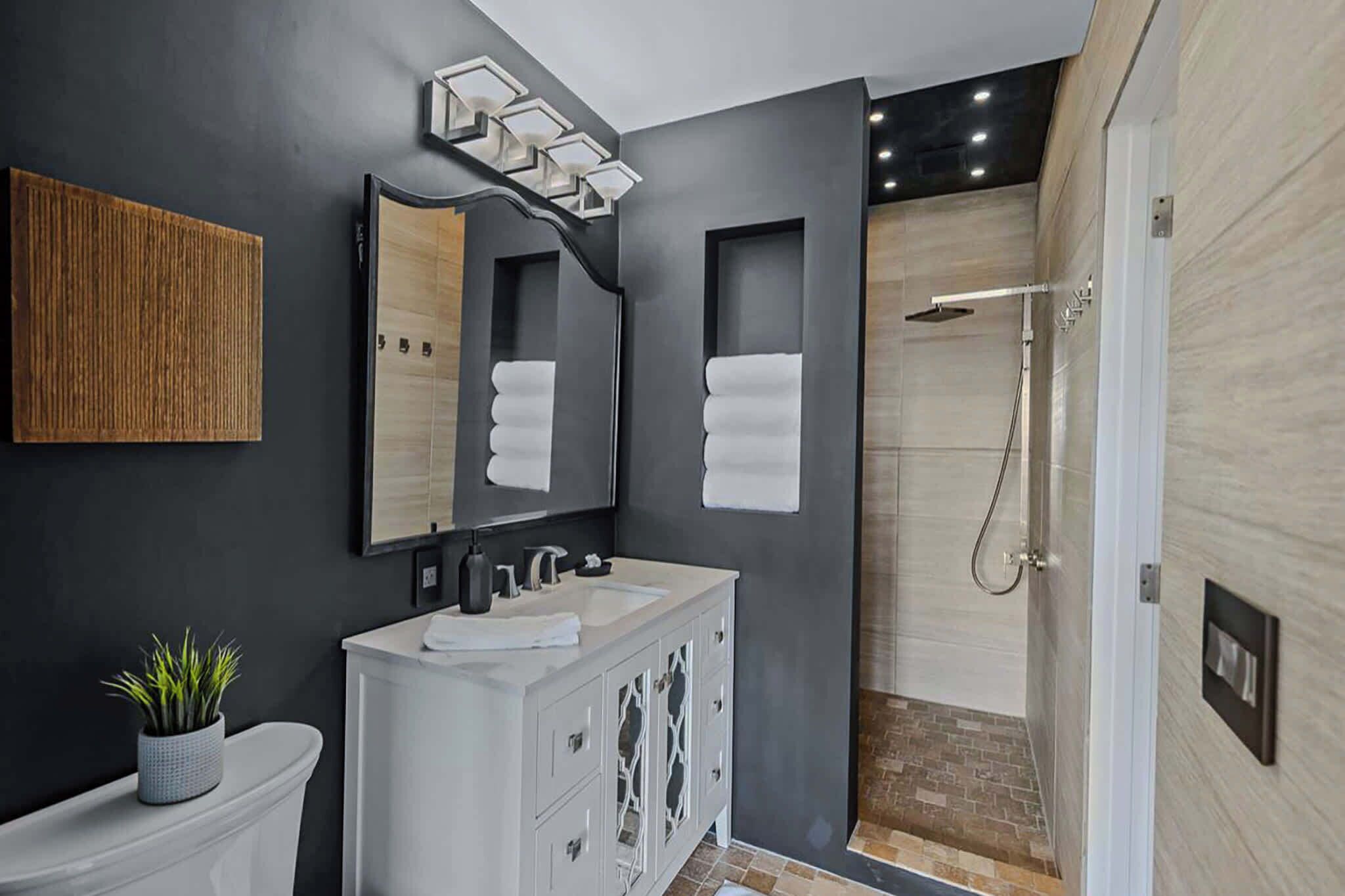 A modern bathroom with a white vanity, a large mirror, and a shower area.
