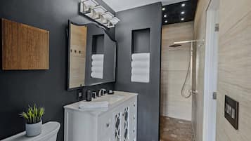 A modern bathroom with a white vanity, a large mirror, and a shower area.