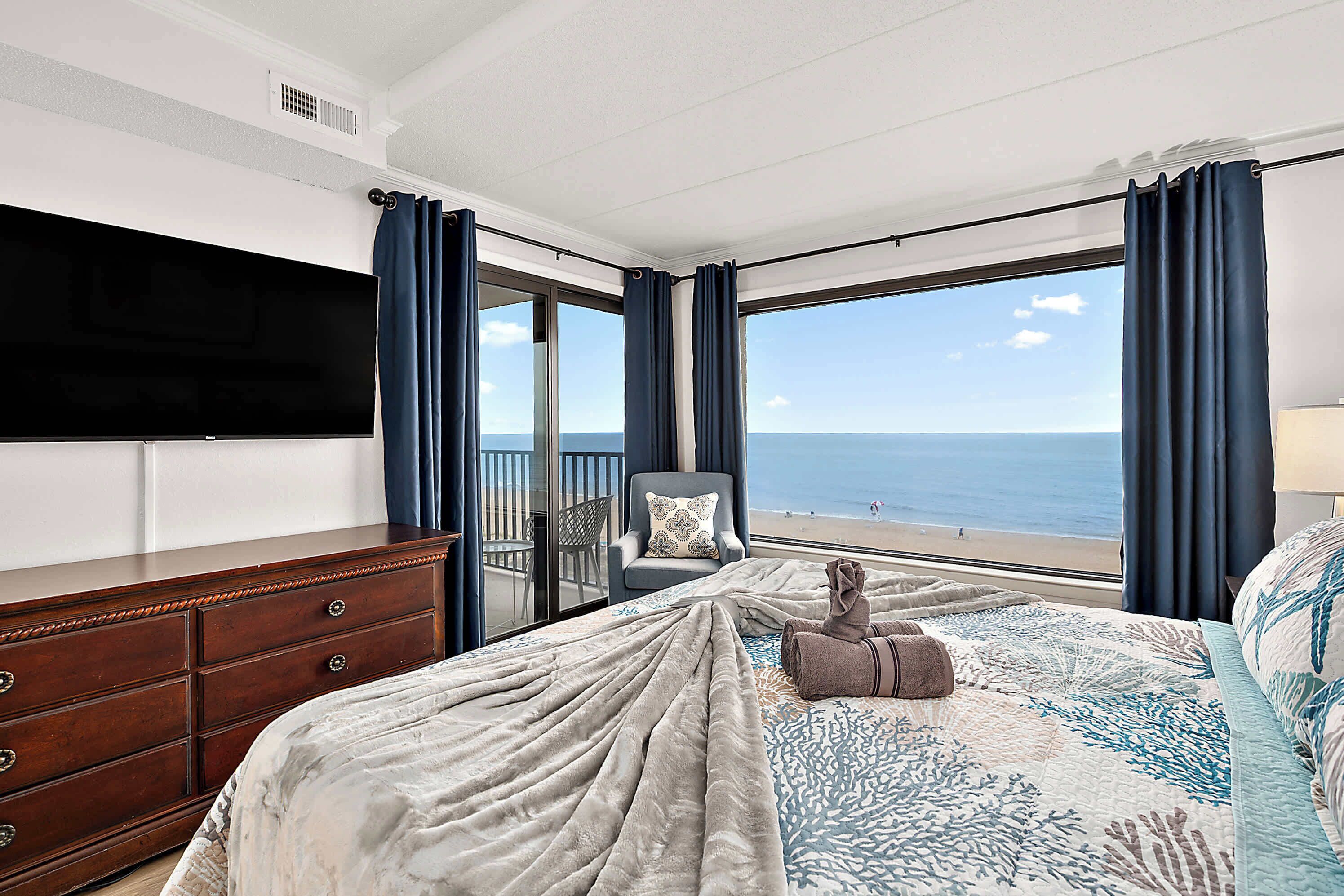 Una camera da letto con un letto grande, una cassettiera, una TV e vista sull'oceano.