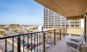 Un balcón con vista a un estacionamiento y un edificio de gran altura.