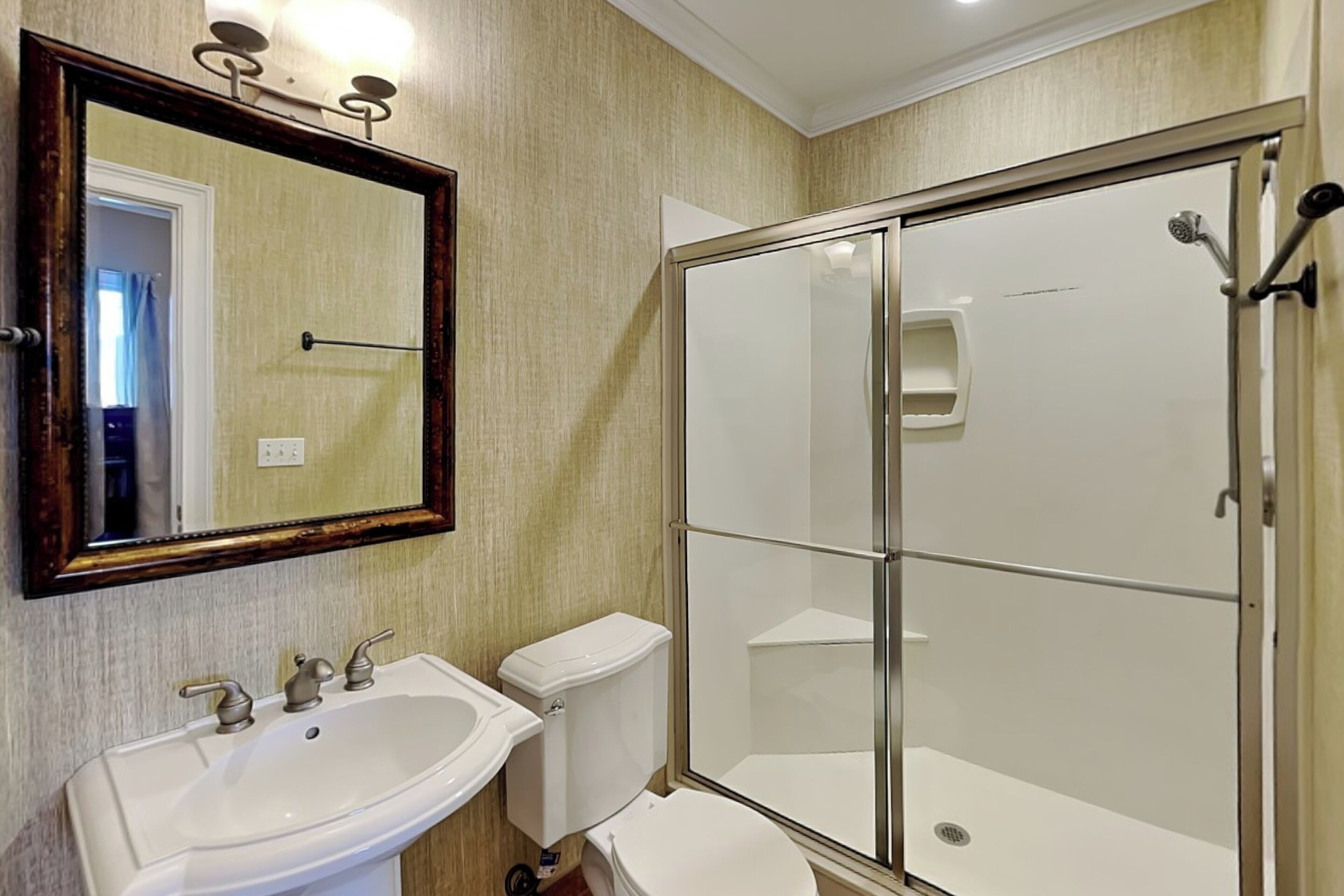 A bathroom with a sink, toilet, and glass-enclosed shower.