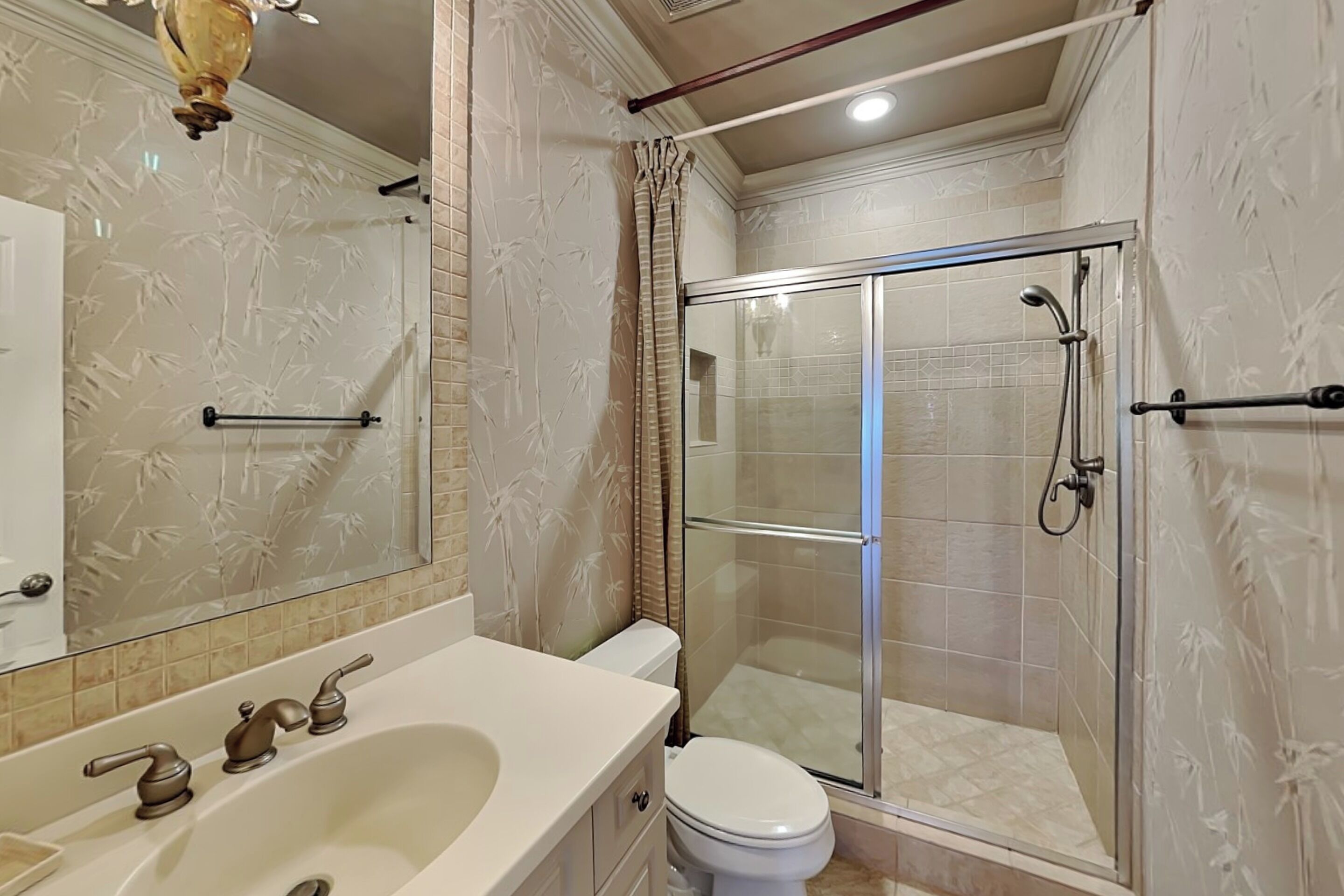 A bathroom with a bathtub, toilet, and glass shower enclosure.