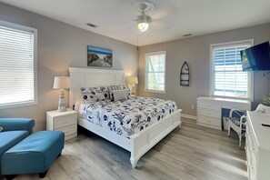 Un dormitorio con cama, escritorio, silla, mesita de noche y televisor.