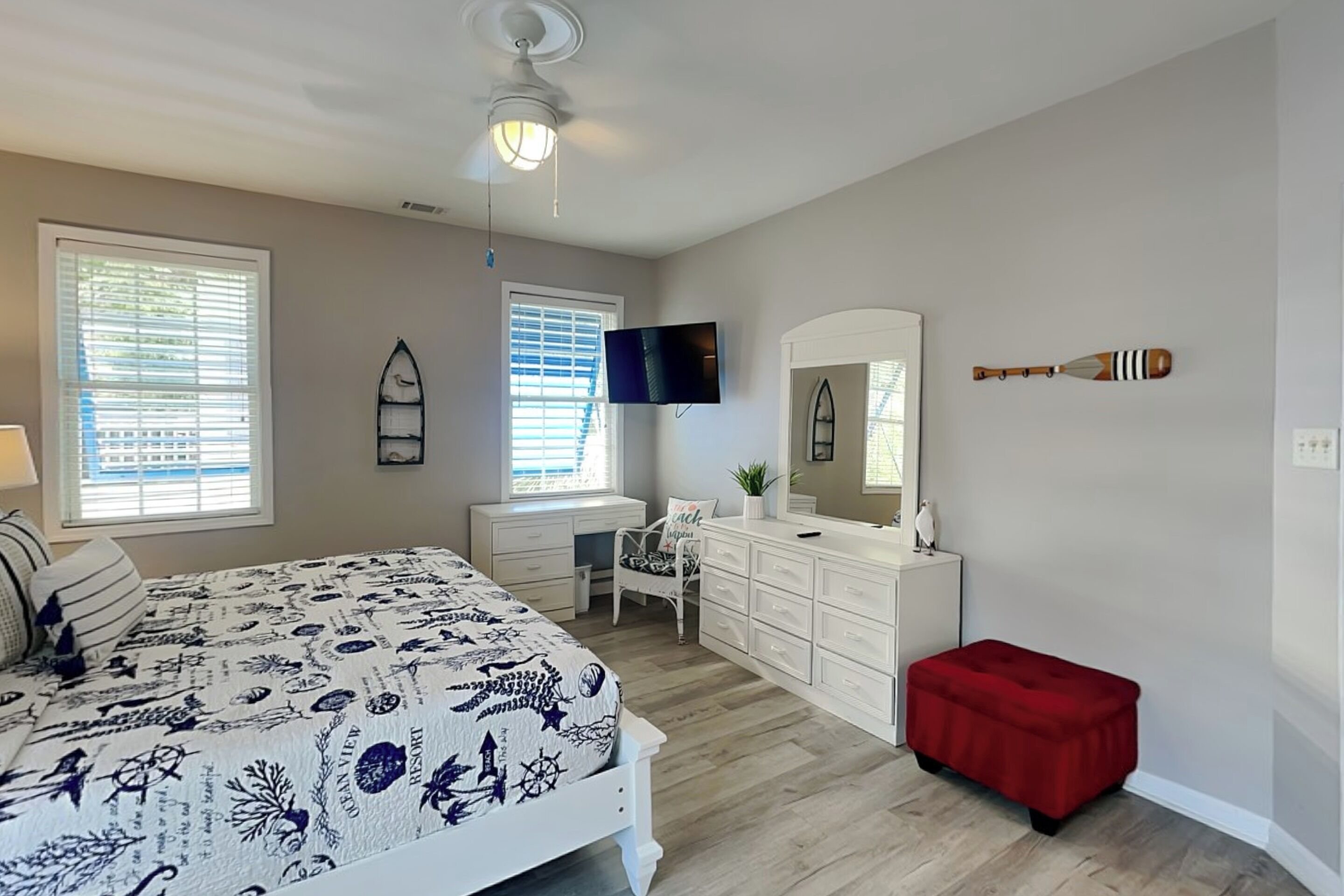 A bedroom with a bed, dresser, vanity, and a red bench.