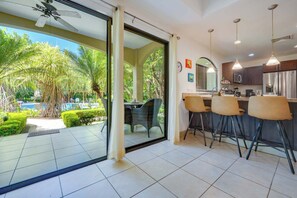 Eine moderne Küche mit Barhocker, einem großen Fenster und Blick auf Pool und Grünanlage.
