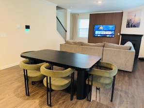 A modern living room with a dining area, a sofa set, a flat-screen TV, and a fireplace. - Family Friendly and Group Stay 4BR Home, Sleeps 8 Near ATL Airport (Fairburn)